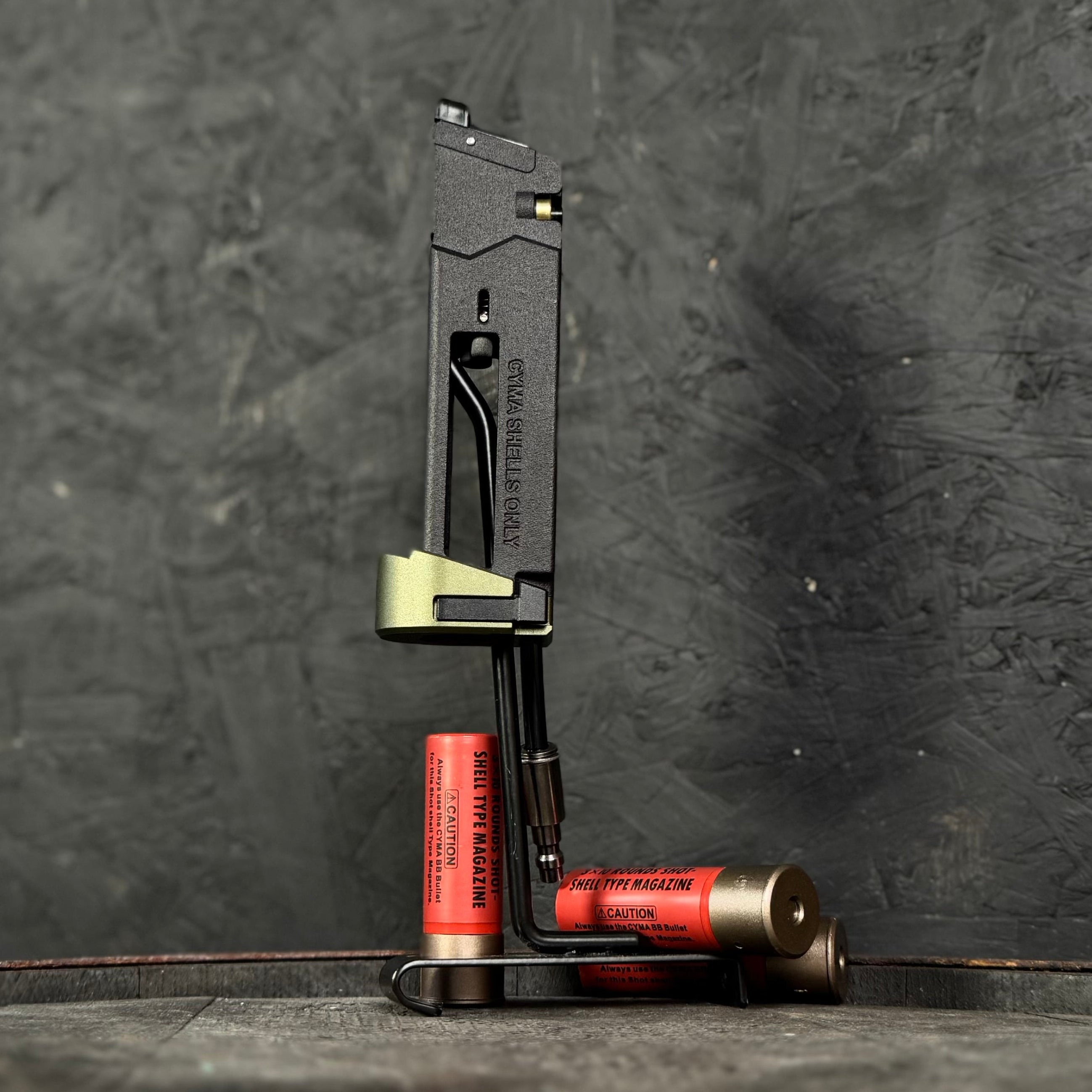 Photo of AIRTAC X T1P MK23/SSX303/SSX23 Shotgun Shell HPA Adapter with a green base on a stand. Shells are seen at the base of the stand