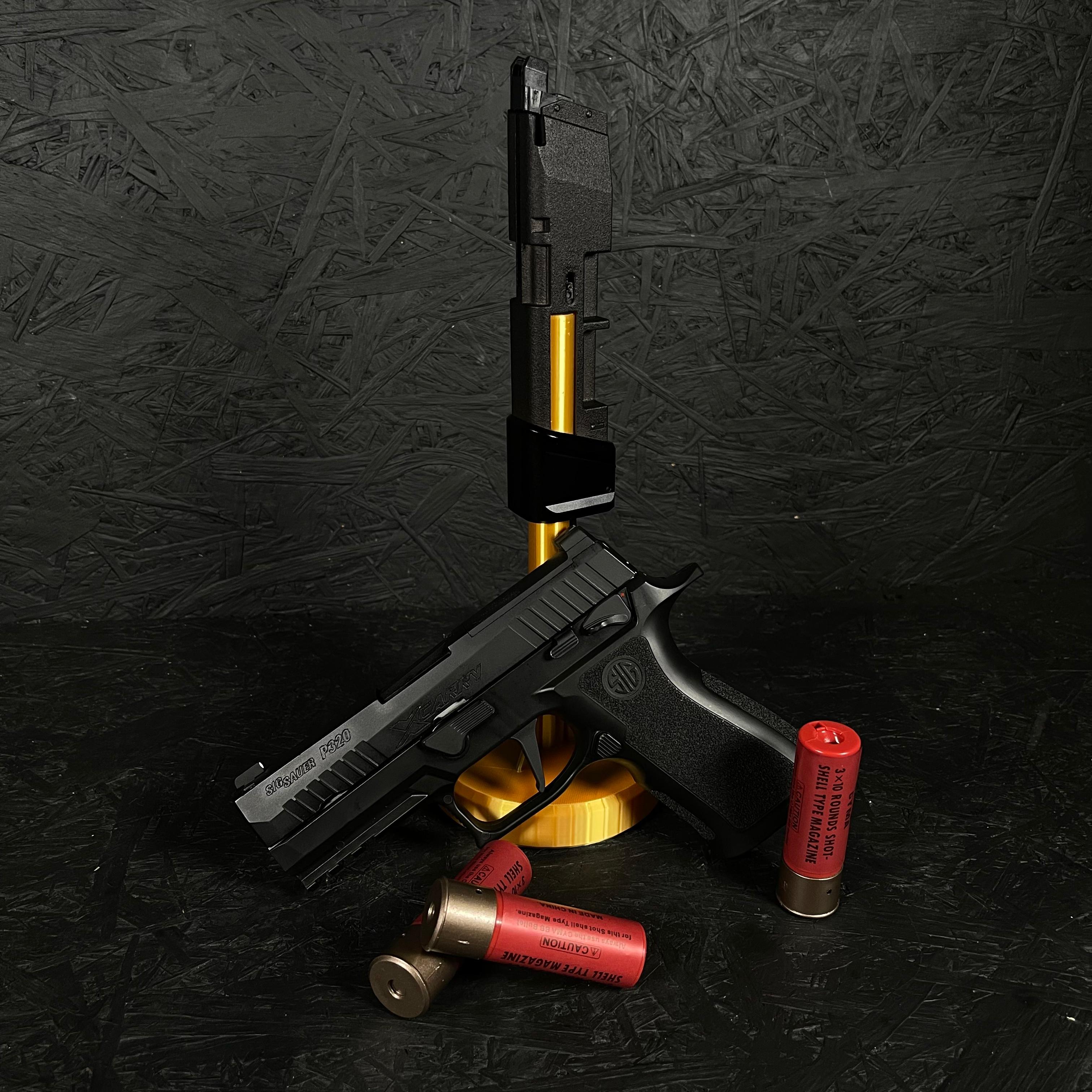 Photo of AIRTAC VFC/SIG M17/M18/XCARRY Shotgun Shell HPA Adapter on a stand at the back of the image. In front is the RIF surrounded by shotgun shells