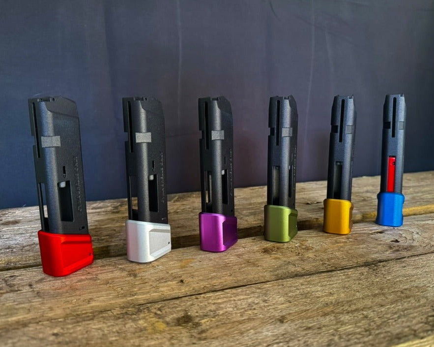 Photo of six AIRTAC X T1P Glock/AAP Shotgun Shell Adapters with different coloured bases - from left to right; red, raw anodized, purple, green, gold and blue